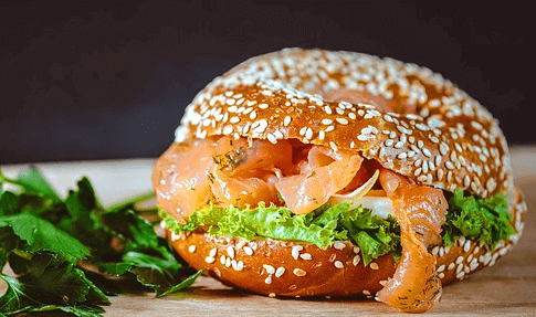 깨가 가득한 둥그런 빵 안에 연어와 상추, 양파가 가득 들어있다.