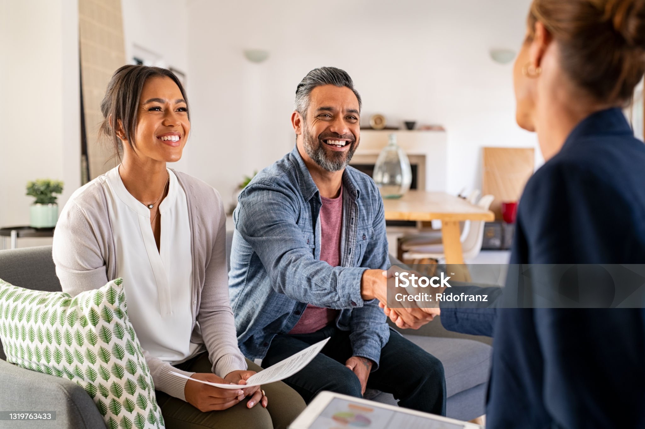 세 명의 사람들이 있고 그 중 남자와 여자가 웃으며 악수하는 사진