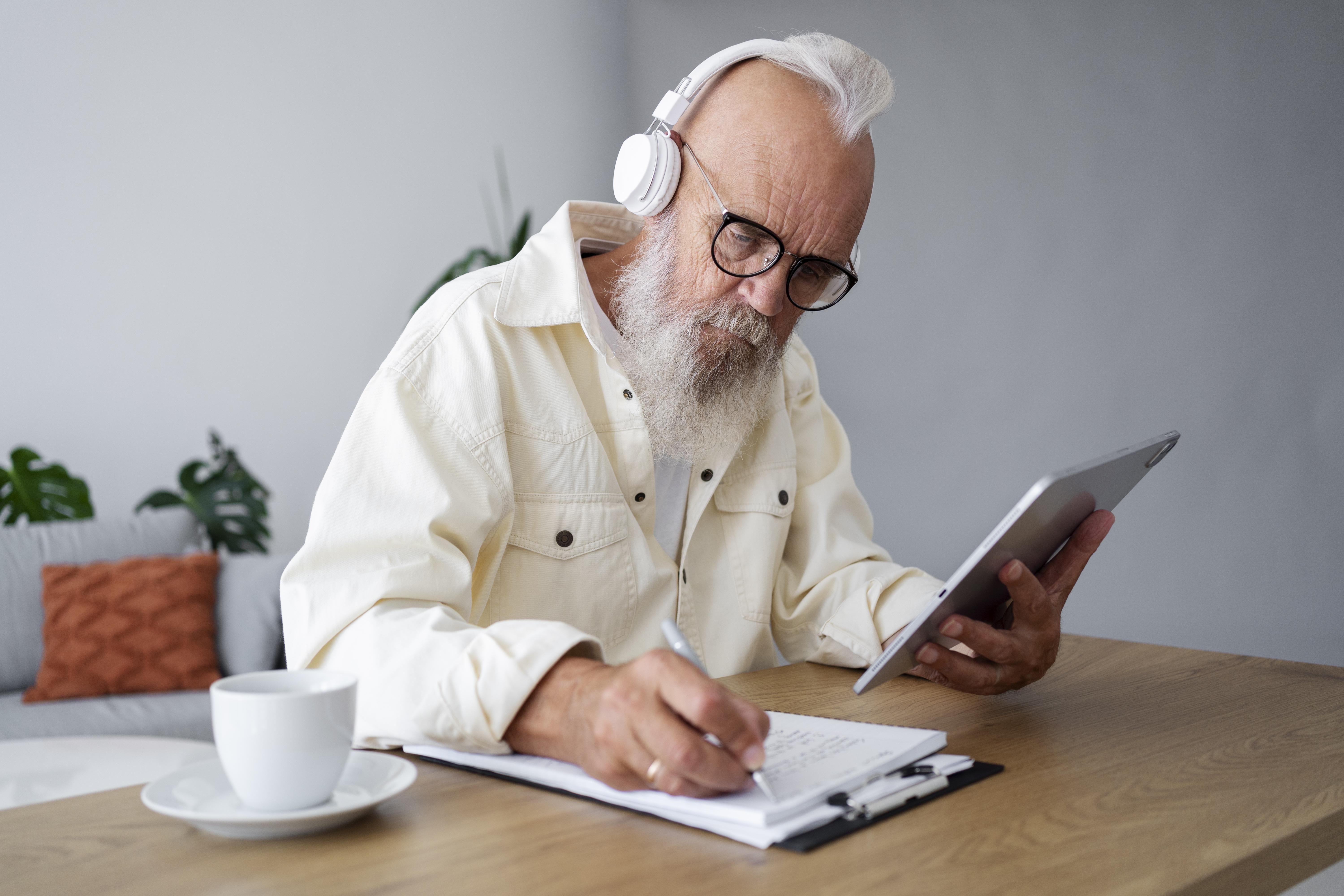 문서를 보며 태블릿으로 확인하는 노년 남성의 모습