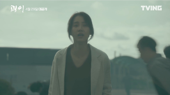 혼란스러운 사람들 사이에서 지친 얼굴로 주변을 살피는 신현빈