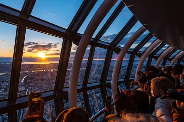 전망대에서 사람들이 떠오르는 해를 바라보고 있는 사진
