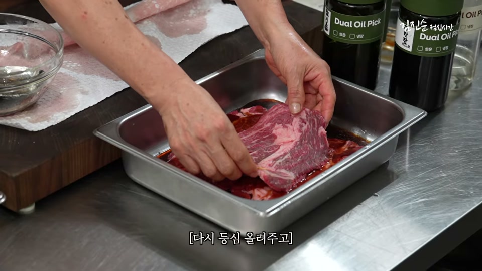 쟁반에 고기를 올리고 양념을 끼얹는 장면