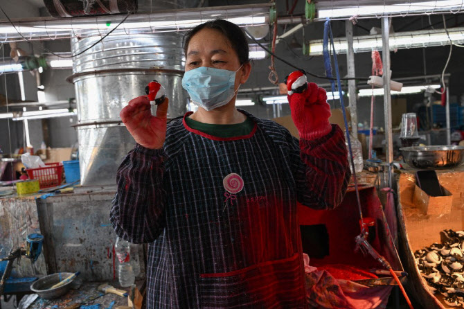 중국 저장성 이우의 플라스틱 제조 공장에서 직원이 장난감 제품을 보여주고 있다.