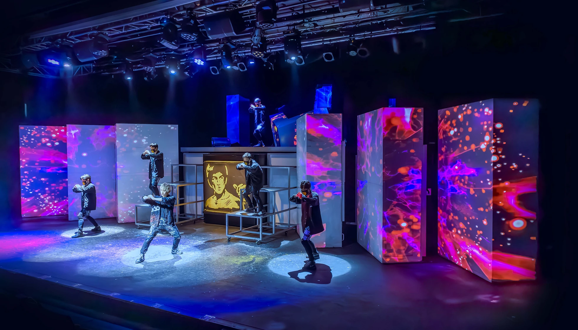 화려한-전광판-앞-검은옷을-입은-사람들이-무대-위에서-춤을-추고있다