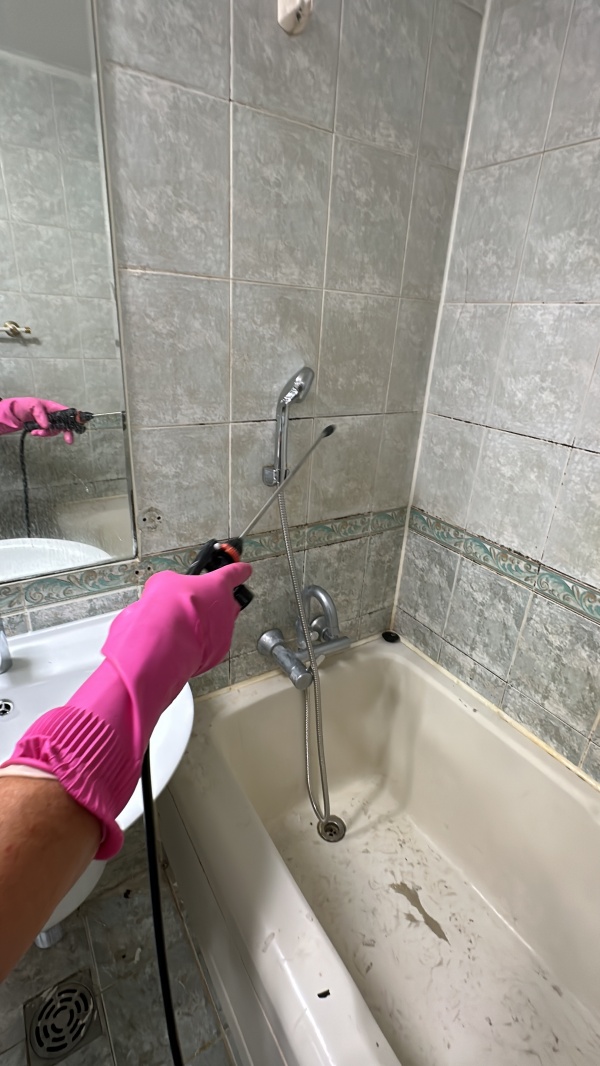 분무기로 약품을 화장실 벽면에 골고루 뿌리고 있습니다.