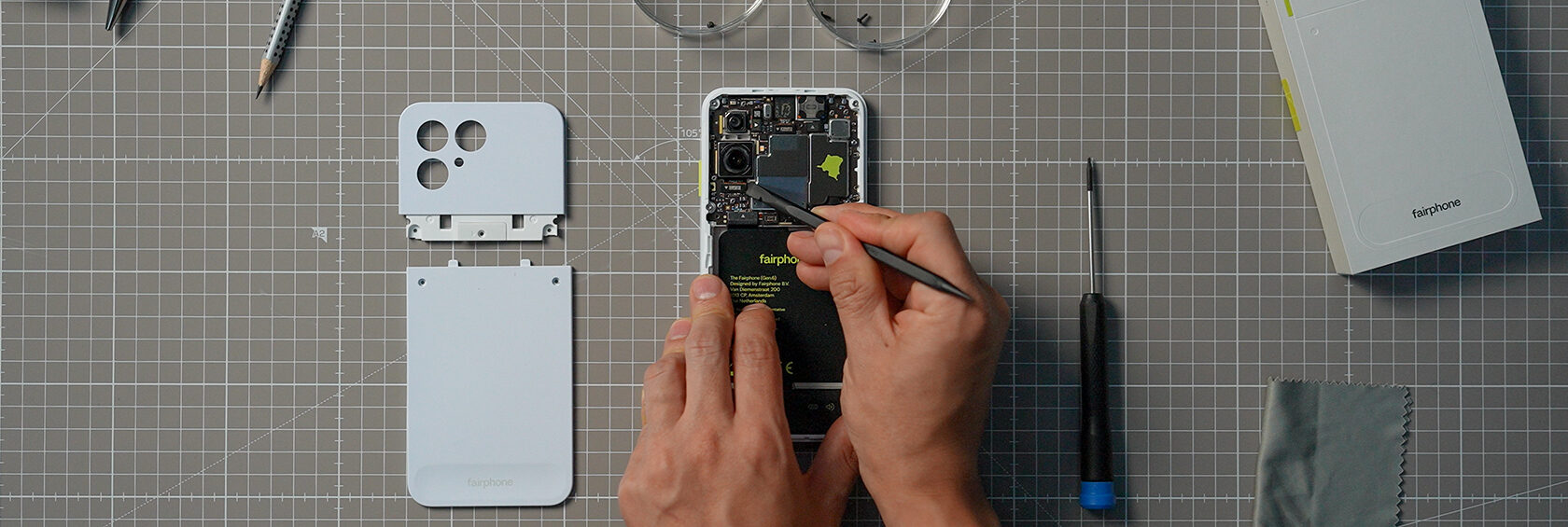 작업 매트 위에서 페어폰(Fairphone) 스마트폰을 분해하여 수리는 모습의 사진입니다.