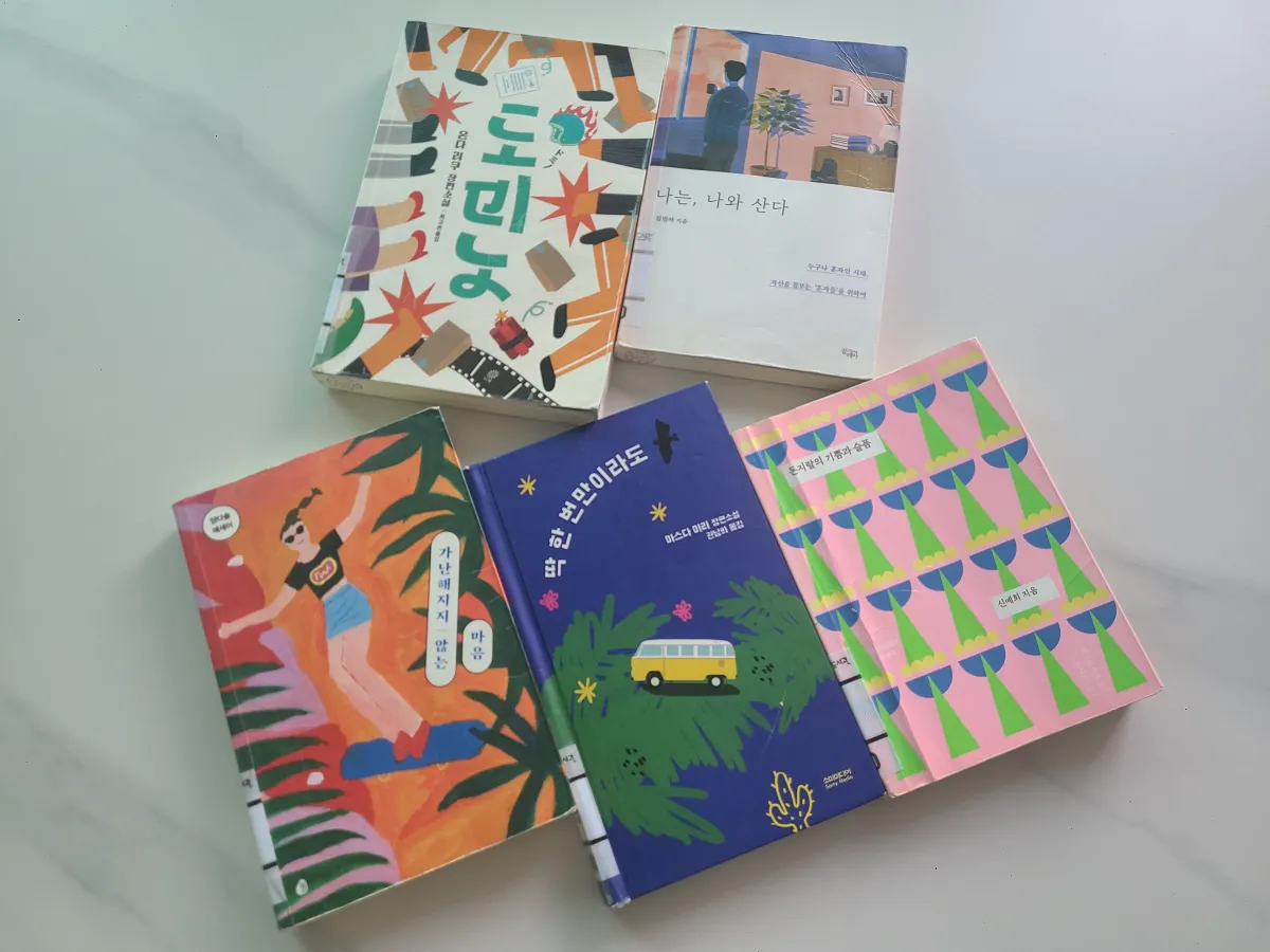 흰테이블위에-올려져있는-책5권-도미노-나는나와산다-가난해지지않는마음-딱한번만이라도-돈지랄의기쁨과슬픔