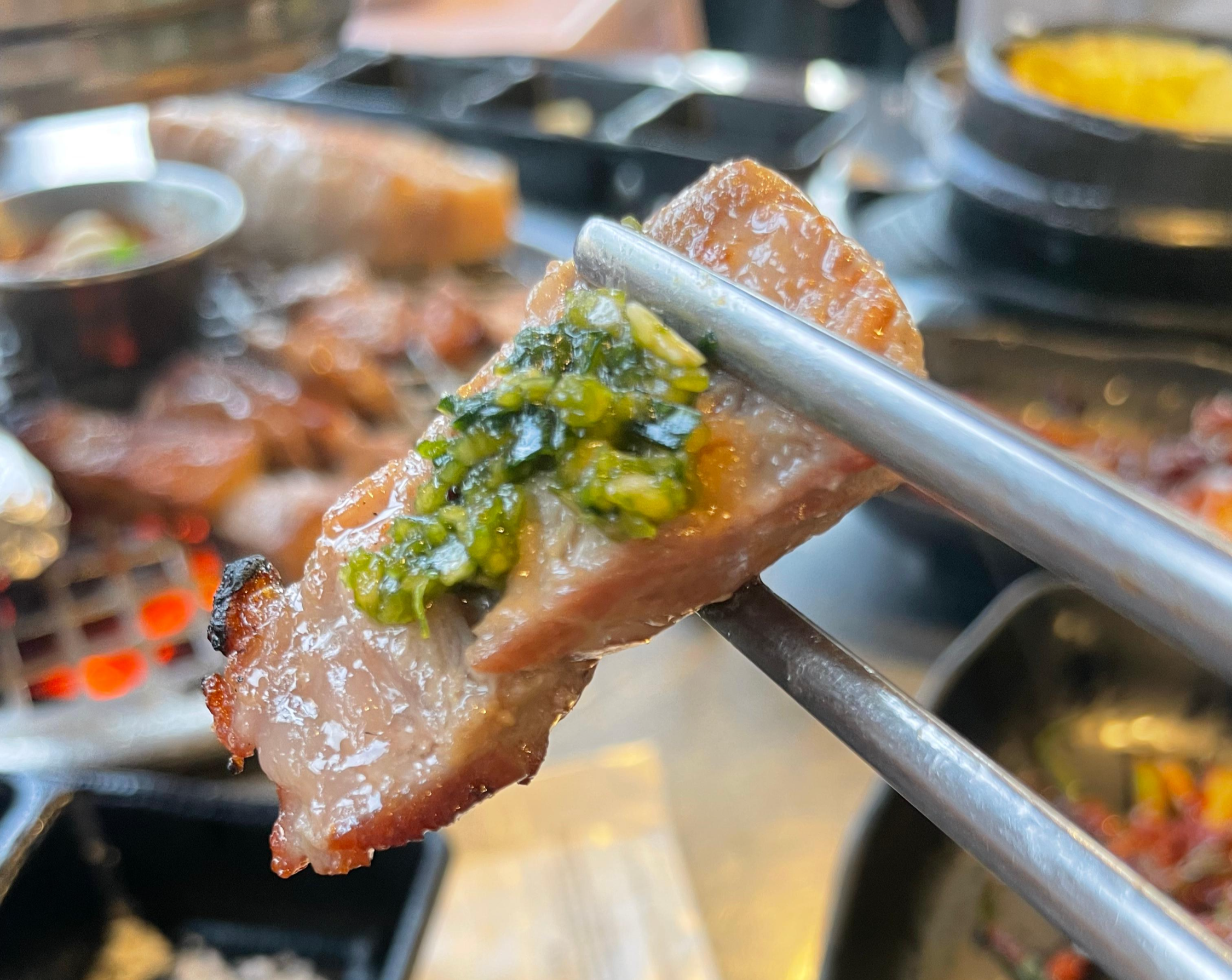 지리산 흑돼지 삼겹살에 바질 마늘 소스를 올려 먹는 모습