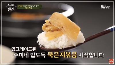 따뜻한 밥에 맛있는 묵은지 볶음이 올려 숟가락으로 한 술 뜬 모습입니다.
