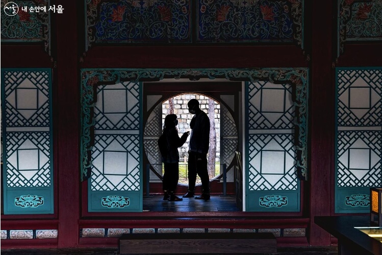 집옥재 열린 만월창 앞에 마주 서 있는 남녀