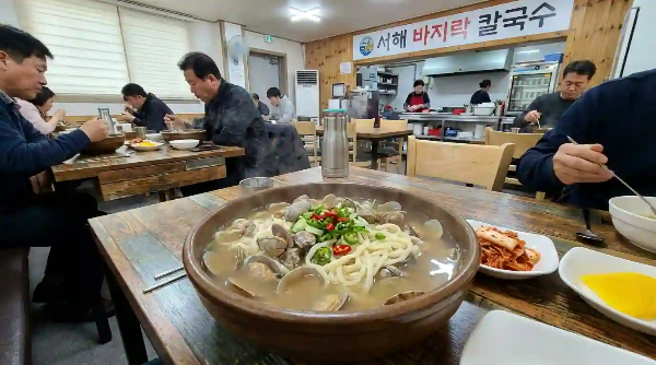 식당에서 바지락 칼국수를 먹고 있는 사람들.