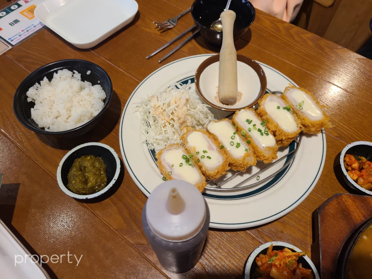 나무로된테이블위에-치즈돈가스-할라피뇨-김치-양배추-작은절구에깨와방망이-검은색공기밥