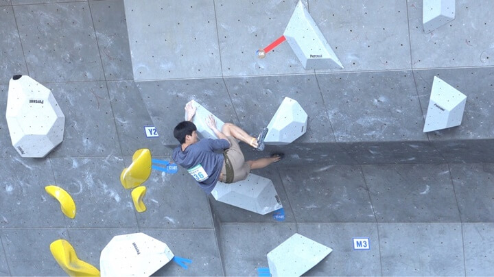 대회에서 한 선수가 볼더링 종목 문제를 풀고있는 사진입니다.