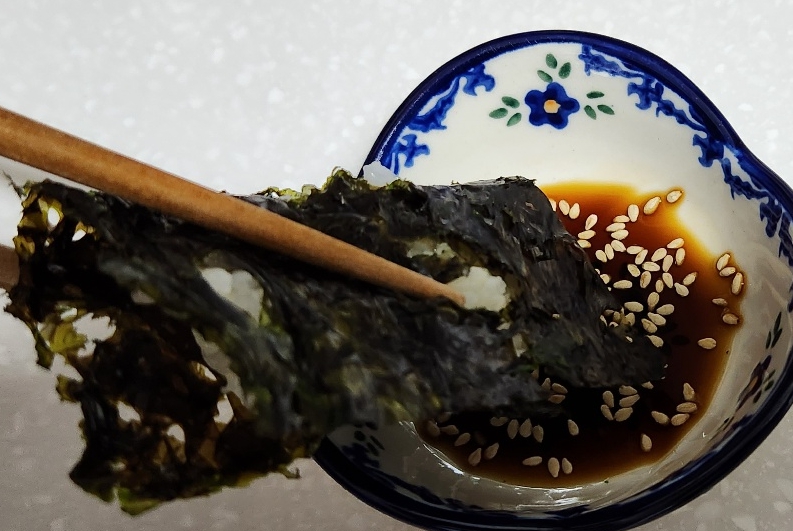 완성된 곱창김에 밥을 넣고 간장소스에 찍는 모습의 사진입니다.