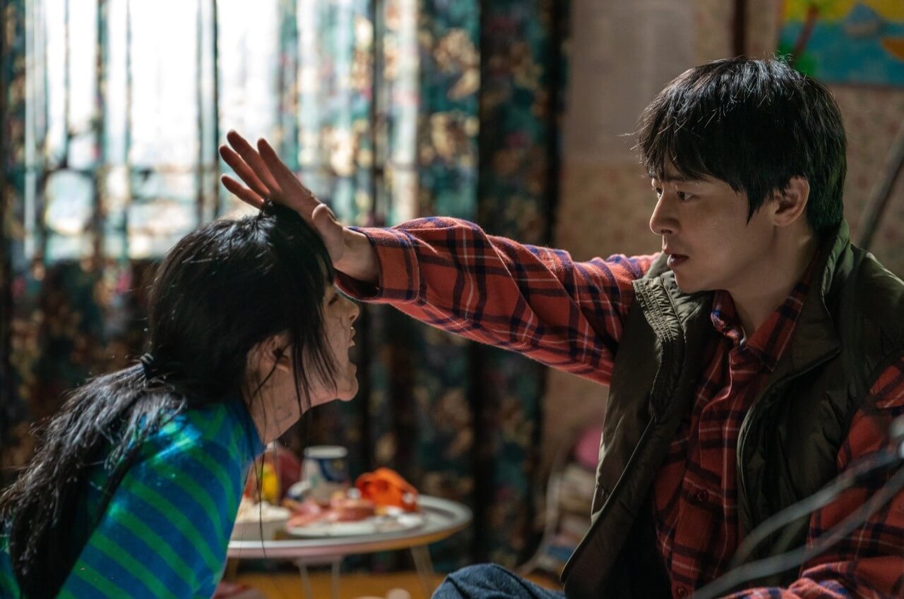 수아가 사람을 물지 못하도록 손으로 수아의 이마를 막아서는 아빠 정환의 모습