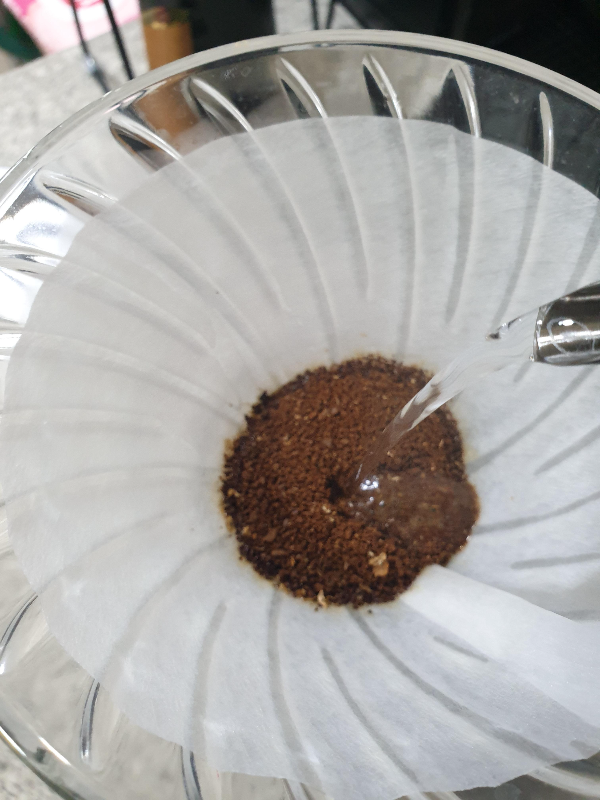 드리퍼 안에 물을 머금은 원두가루가 있다. 그 원두에 추가로 물을 붓는 모습