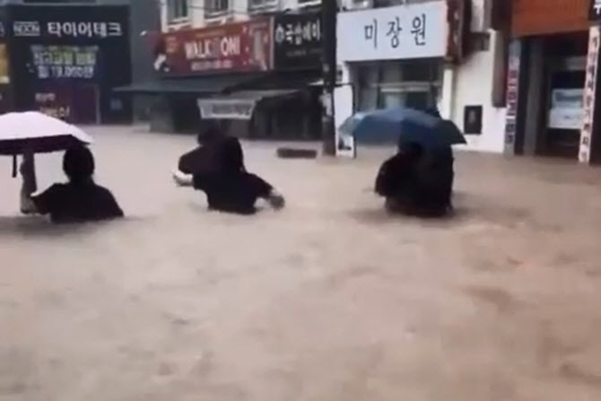 폭우가 쏟아진 지난 17일 오후 광주 북구 용봉동 거리에서 시민과 학생이 가슴 높이까지 차오른 흙탕물을 헤치며 귀가하는 사진