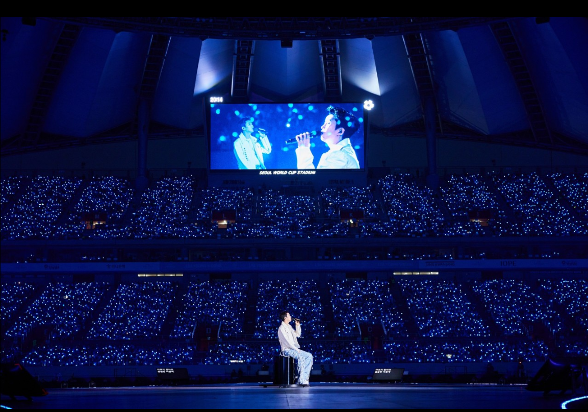 임영웅 콘서트 영화이 한 장면. 임영웅이 앉아서 노래를 부르고 있다.