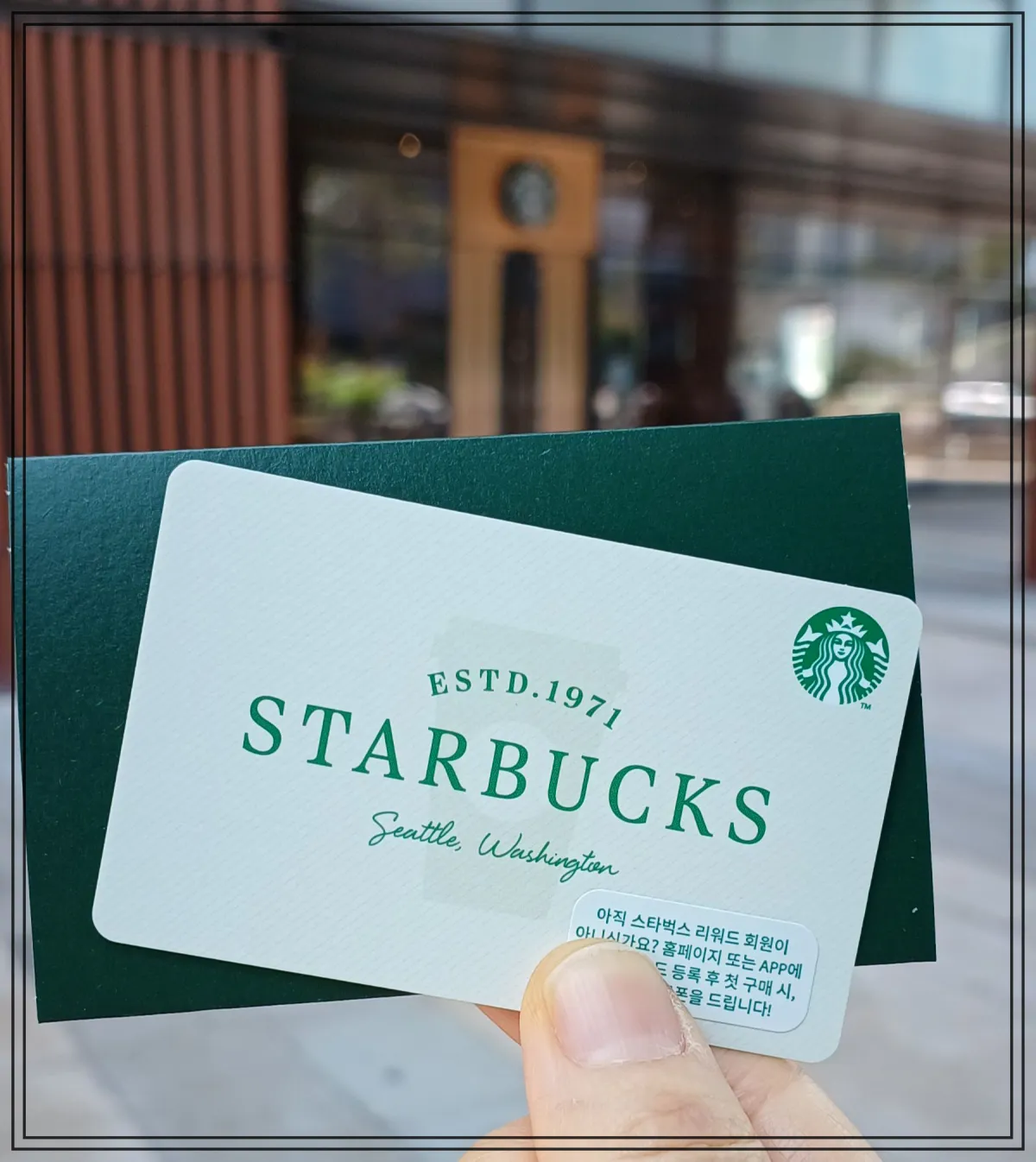 초록색-카드봉투-앞에-하얀-스타벅스-기프티-카드-위에는-커피-매장-어렴풋이-보임