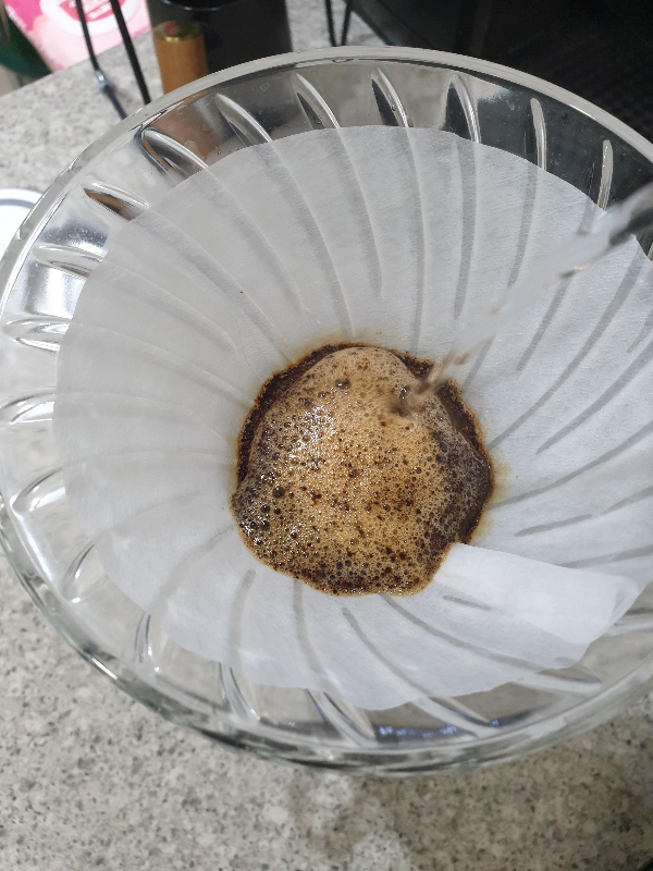 추가로 물을 푸어하는 모습. 원두 가루와 물이 반응해 거품이 일고 있다.