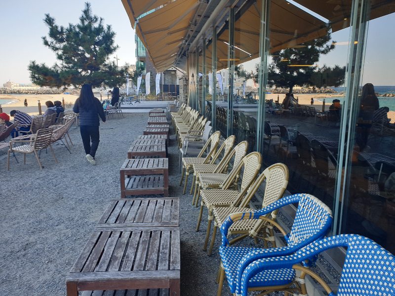 해변과 카페 유리 사이에 좌석들이 배치되어 있다.