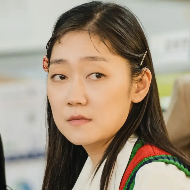 흰셔츠에 초록 쪼끼를 입고 긴머리에 머리핀을 꼽고 앉아 있는 드라마 이 연애는 불가항력의 손새별 캐릭터