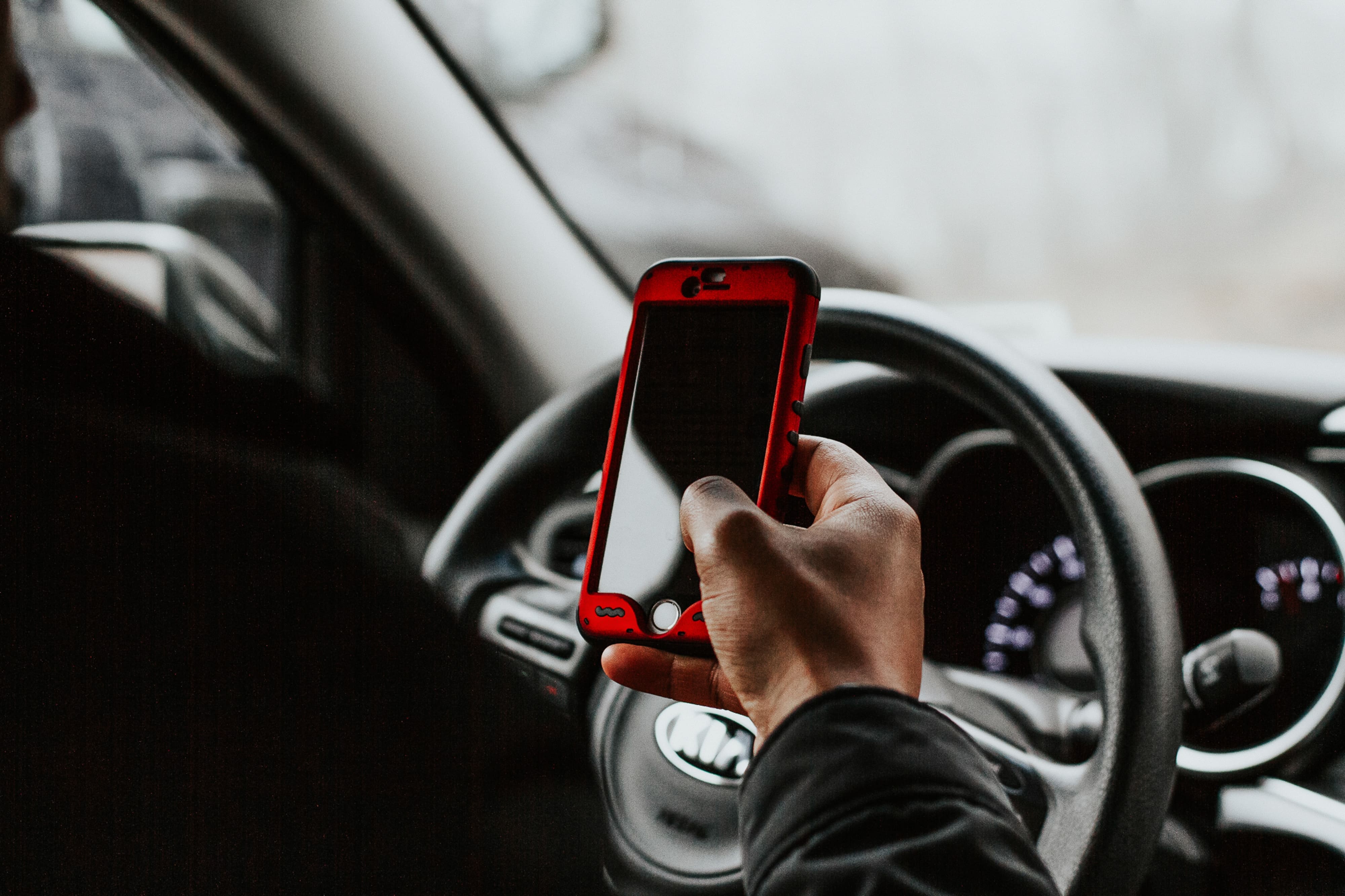 A photo of a smartphone that appears to be steering a car without holding the steering wheel