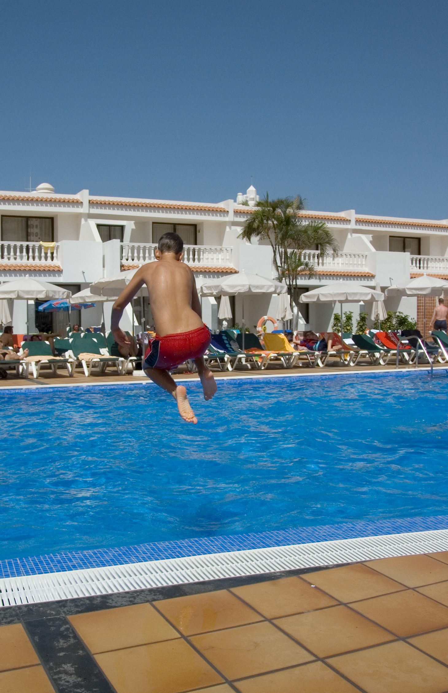 남자 아이가 수영장 물속으로 뛰어드는 사진