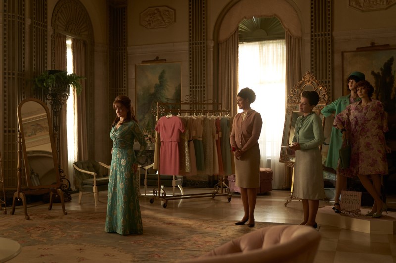 여자 2명이 초록색 원피스를 입은 여성을 보고 있다.