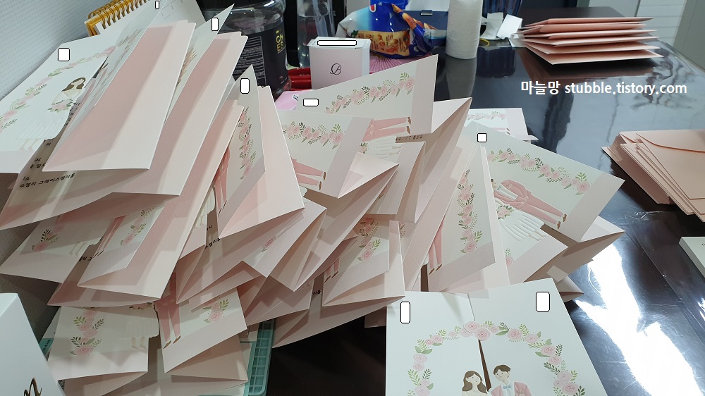 식탁위에 접힌 청첩장이 이리저리 쌓여있다.