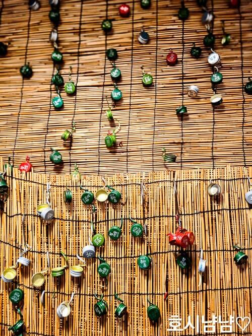 하남 인삼한약막걸리 벽 한 켠에 소주뚜껑들이 주렁주렁 달려 있는 모습