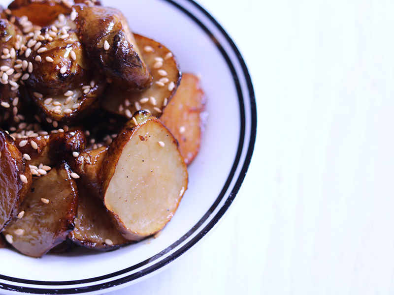 돼지감자 오븐 볶음. 흰접시에 깨를 뿌려 담았다.