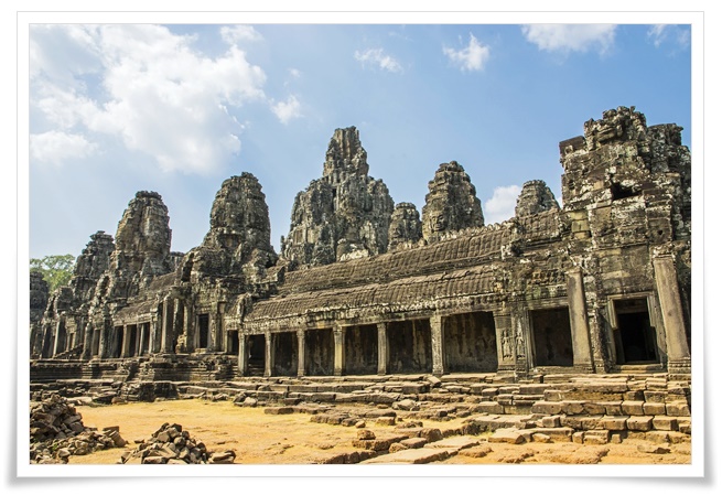 고대 앙코르 유적지내의 바이욘 사원 모습, 햇빛 아래 여러 개의 석조 탑과 여러개의 기둥들이 나란하게 서있는 열주 건축양식이 보이는 전경