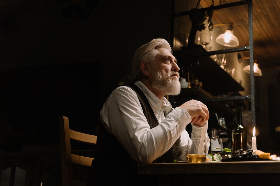 Senior man enjoying a quiet meal by candlelight in a cozy and elegant indoor setting.