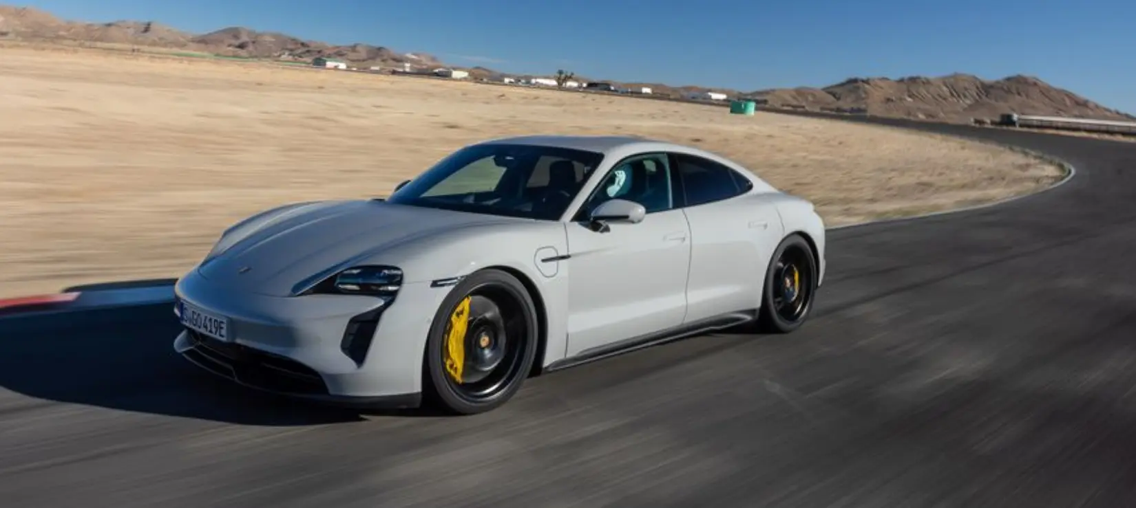 2024-포르쉐-타이칸-GTS가-도로를-주행하는-측면-사진으로-회색의-색상과-뒤의-사막-배경이-어우러진다.
