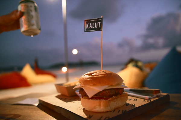 칼룻(KALUT) 깃발을 꽃고 있는 햄버거 그리고 손으로 들고 있는 맥주