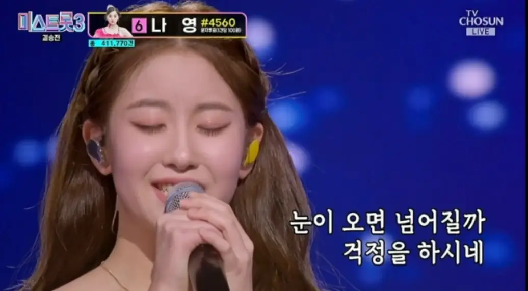 미스트롯3- 파란배경 앞 두눈을 감고 두손으로 마이크를 든채 노래하는 오유진