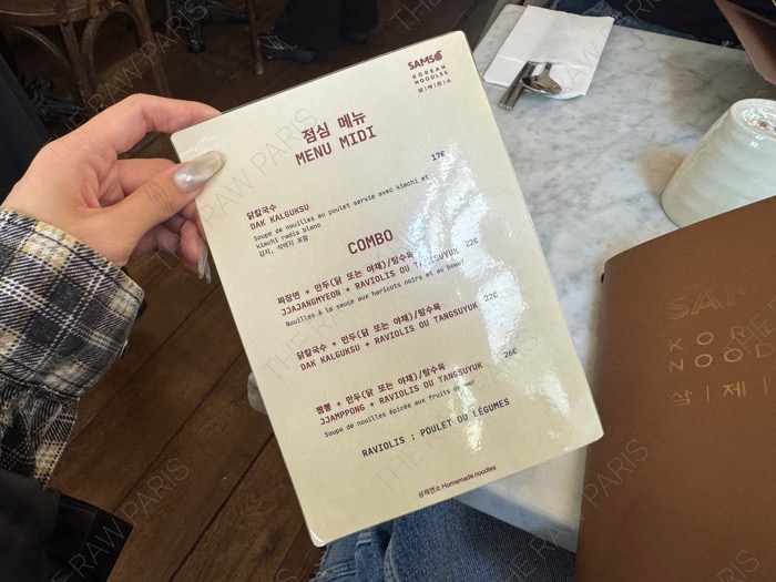 A hand holding the lunch menu card titled MENU MIDI COMBO at SAMSO restaurant in Paris ❘ Une main tenant la carte du menu du midi chez SAMSO
