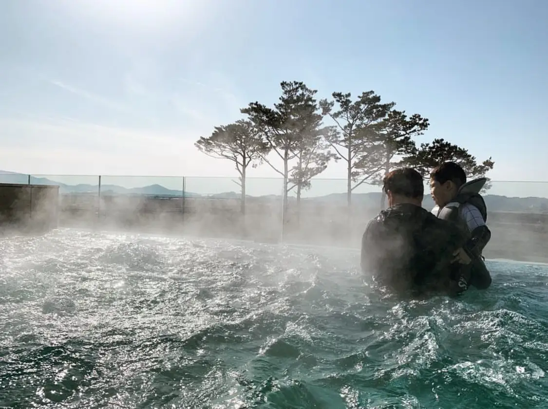 소나무가-보이는-야외-수영장-안에서-어린-아들을-안고-있는-아빠