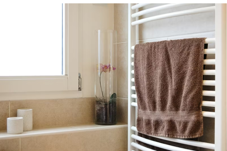 욕실 창가에 젖은 수건과 유리화병, 겨울철 실내 습도 관리를 위한 생활 속 예시