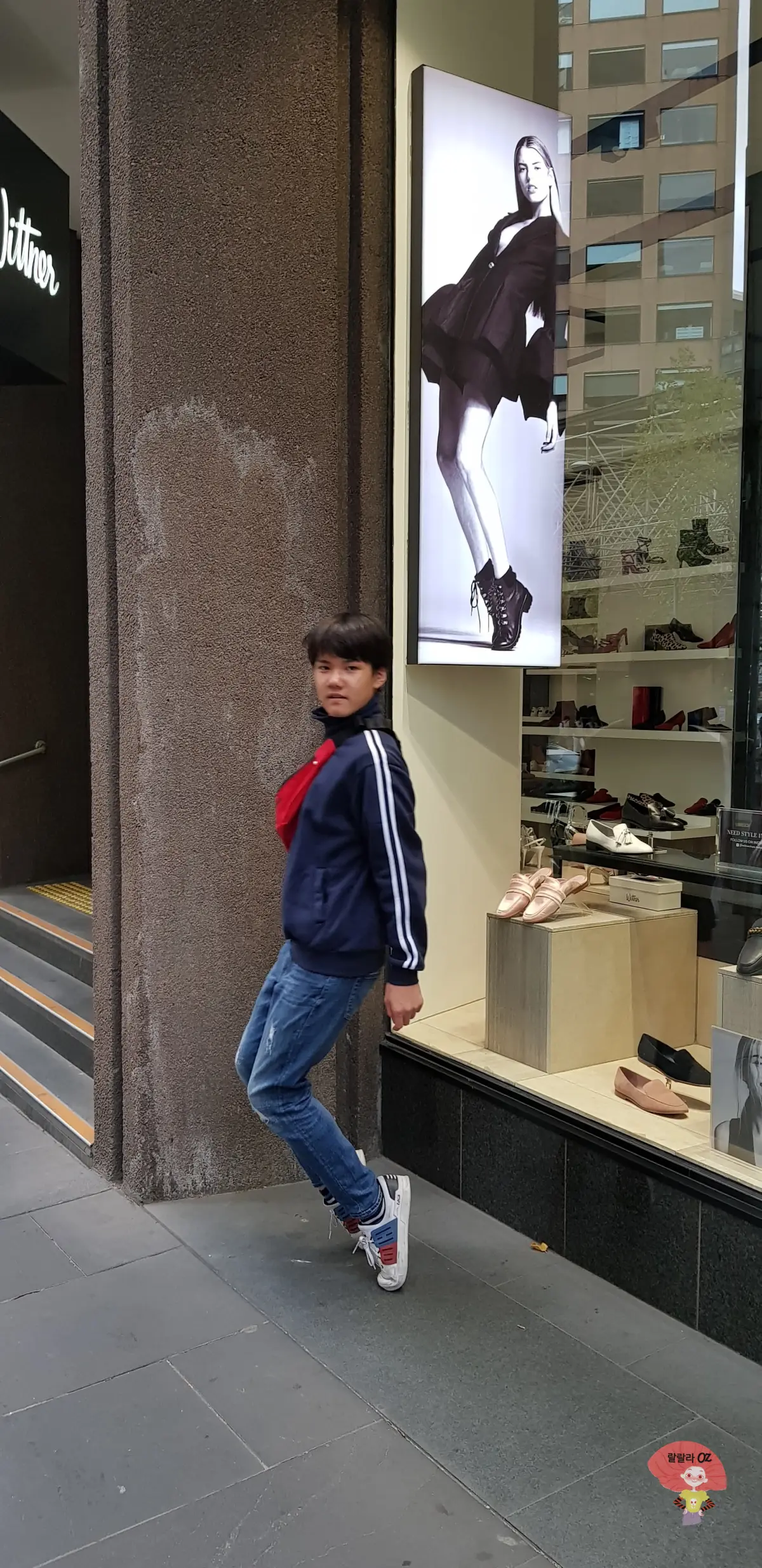 호주-멜버른-어느-거리에서-신발가게-포스터의-모델포즈를-따라하고-있는-소년