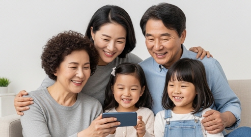 가족이 함께 스마트폰 화면을 바라보며 환하게 웃는 모습