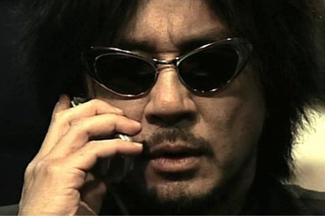 올드보이 한장면으로 오대수(최민식 배우)가 썬그라스를 낀 모습으로 핸드폰 통화를 하고 있다.