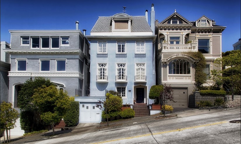 약간 경사진 땅에 푸른 하늘을 배경으로 예쁜 집들이 있는 사진