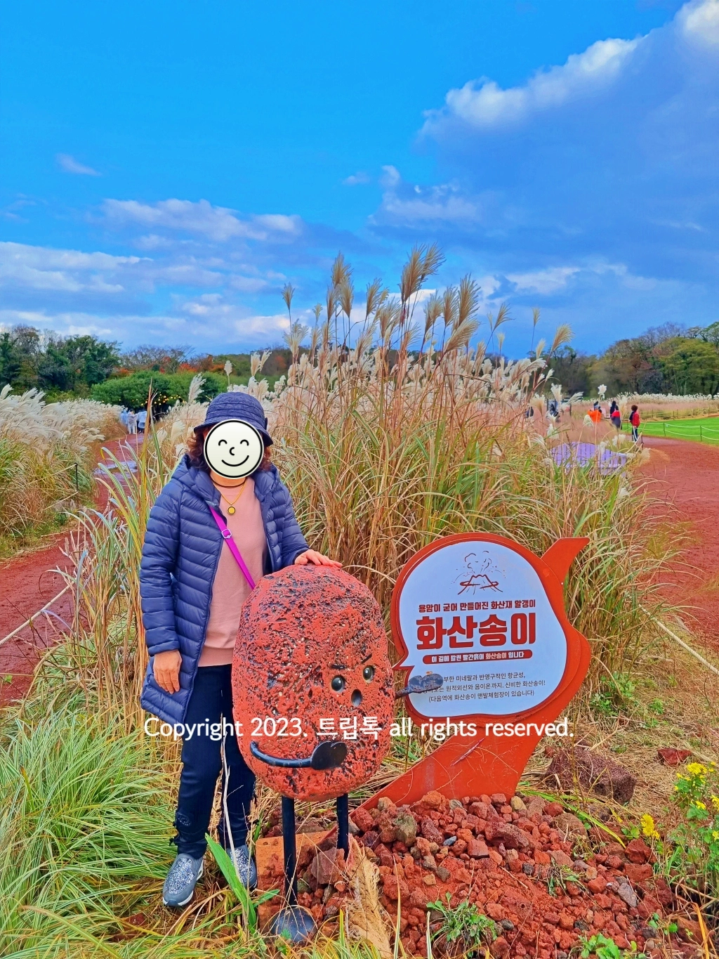 파란하늘아래 화산석으로 만든 캐릭터와 한사람이 있다