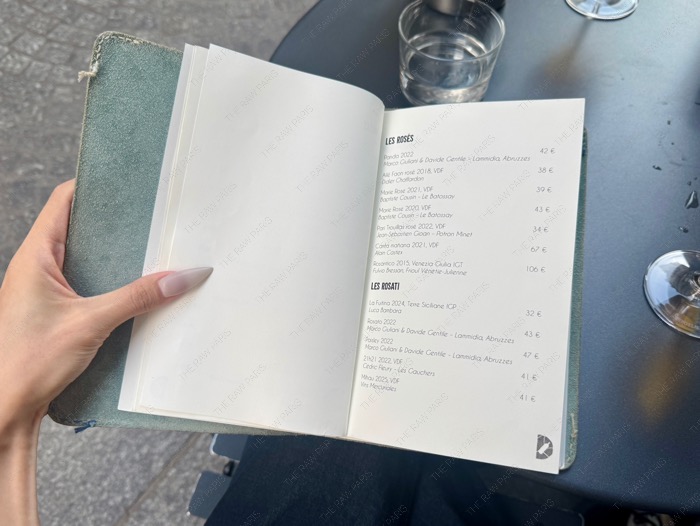 Leather-bound wine menu at Le Dénicheur showing curated rosé and natural wine selections in Paris