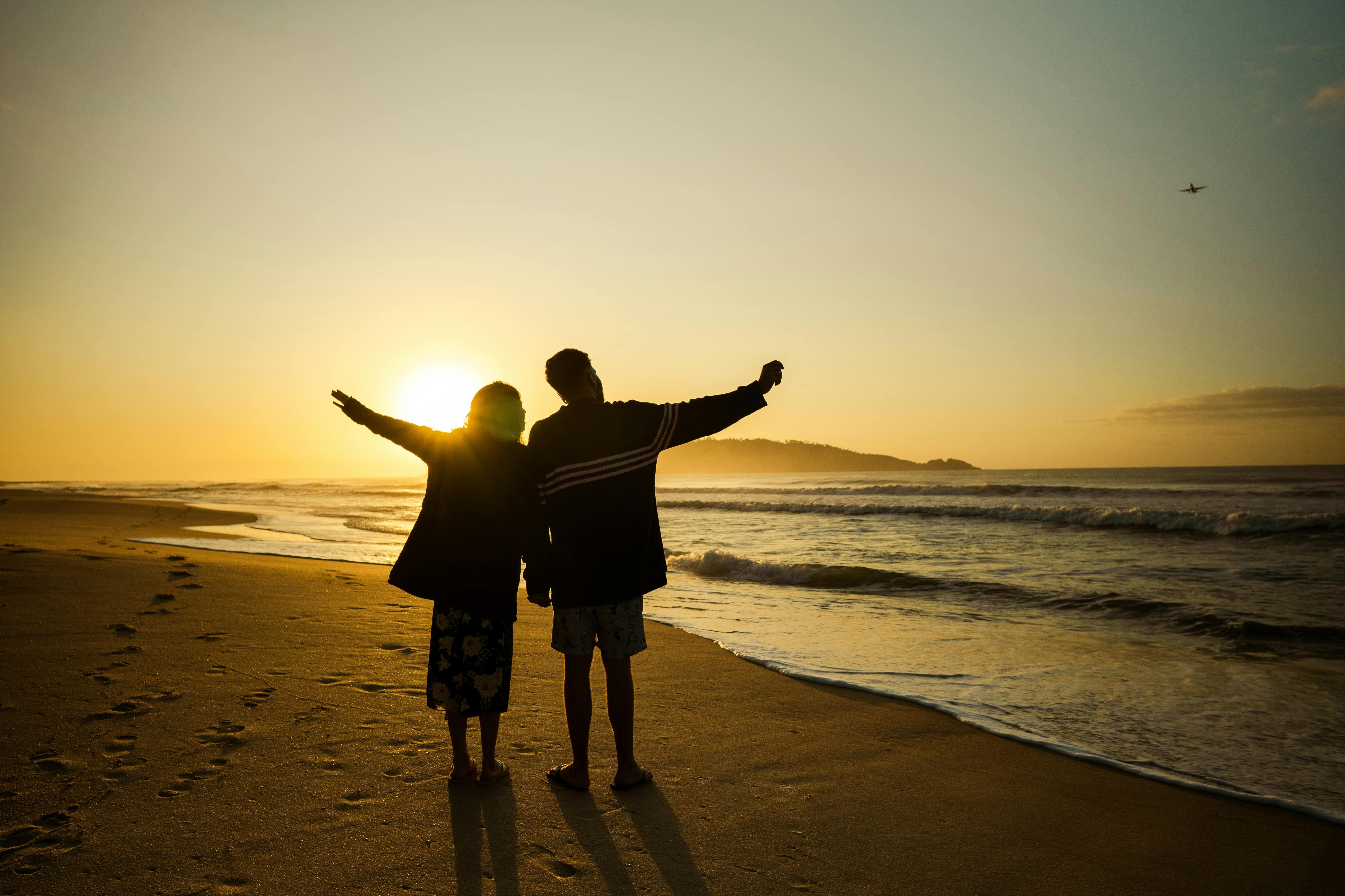 "중년 부부가 바닷가에서 함께 해지는 풍경을 바라보며 걸어가는 뒷모습"