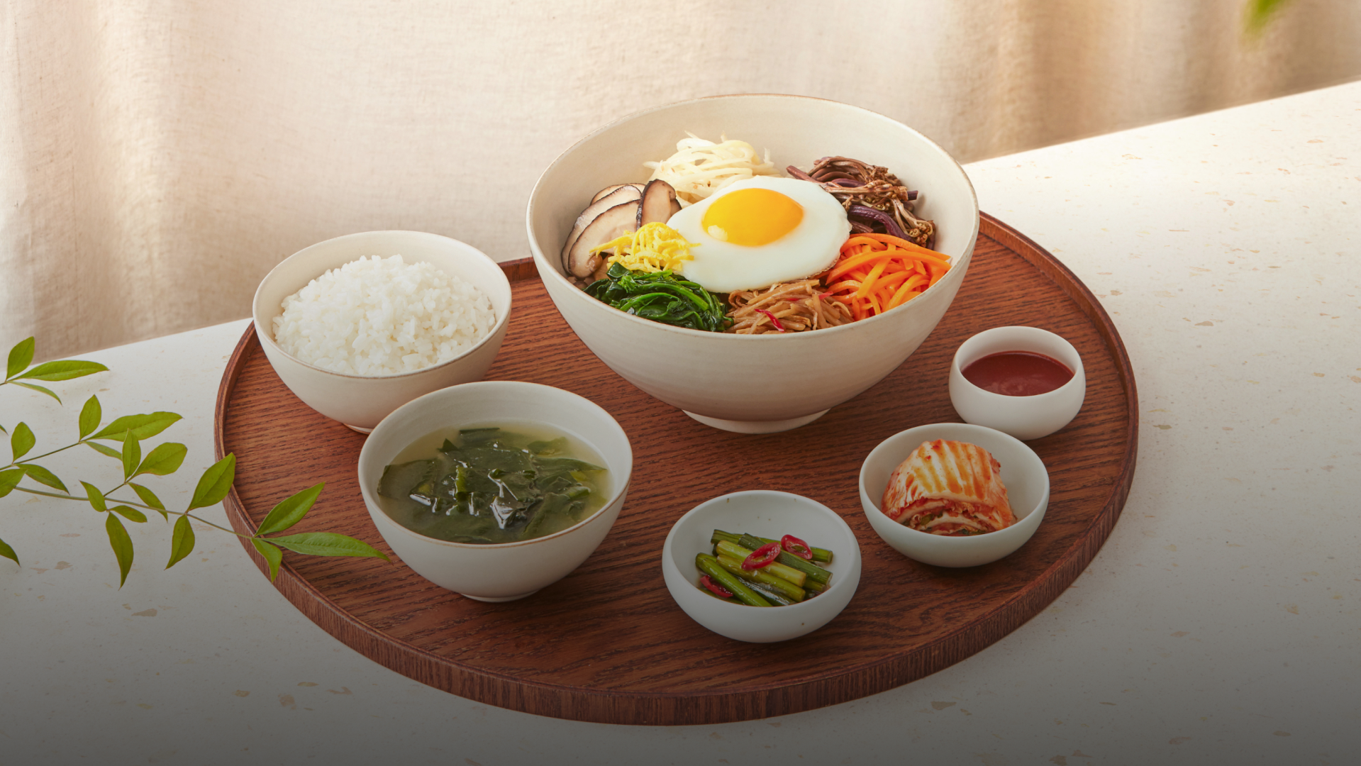 비빔밥과 오이냉국&amp;#44; 마늘짱아찌&amp;#44; 김치가 반달모양 나무접시위에 놓여진 모습