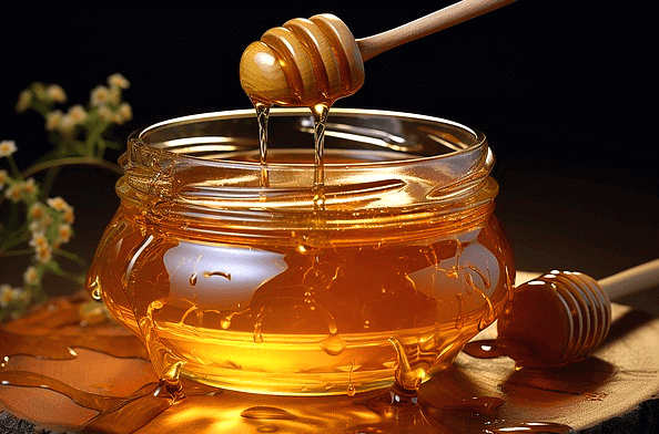 투명한 유리병에 꿀이 가득 들어있다. 나무 꿀주걱으로 꿀을 뜨고있다.