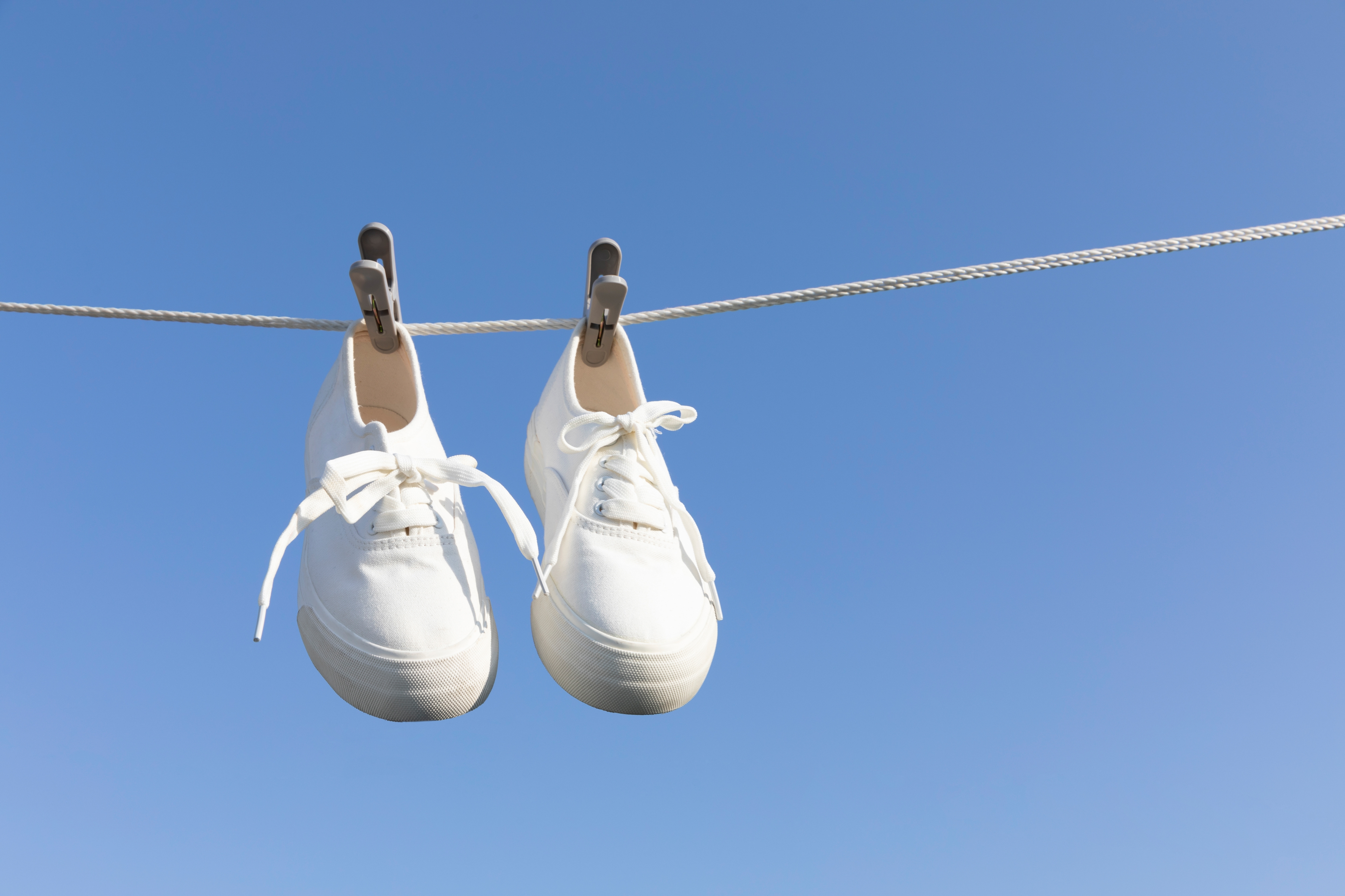 햇빛 아래 빨랫줄에 널린 흰 운동화, 신발 냄새 제거와 환기를 위한 여름철 악취 방지 루틴 예시